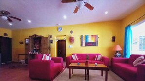 A living room with red sofas, a wooden coffee table, and a ceiling fan.