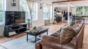 Ein geräumiges Wohnzimmer mit einer Ledersofa, einem Fernseher und einer Essecke mit Tisch und Stühlen.