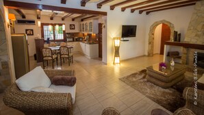 Un amplio espacio de sala con chimenea, un comedor con mesa y sillas, y una cocina al fondo.