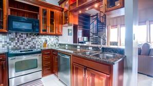 Una cocina con armarios de madera, estufa de acero inoxidable, microondas y encimera de granito.