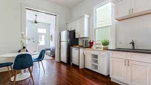 Una cocina moderna con armarios blancos, un refrigerador negro y una zona de comedor con sillas azules.
