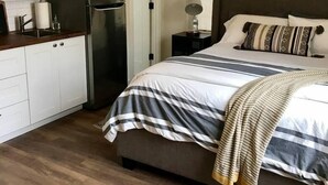 A compact bedroom with a bed, bedside table, and a window. - 209-LG Studio in Center of San Pedro Sq. San Jose! (San Jose)