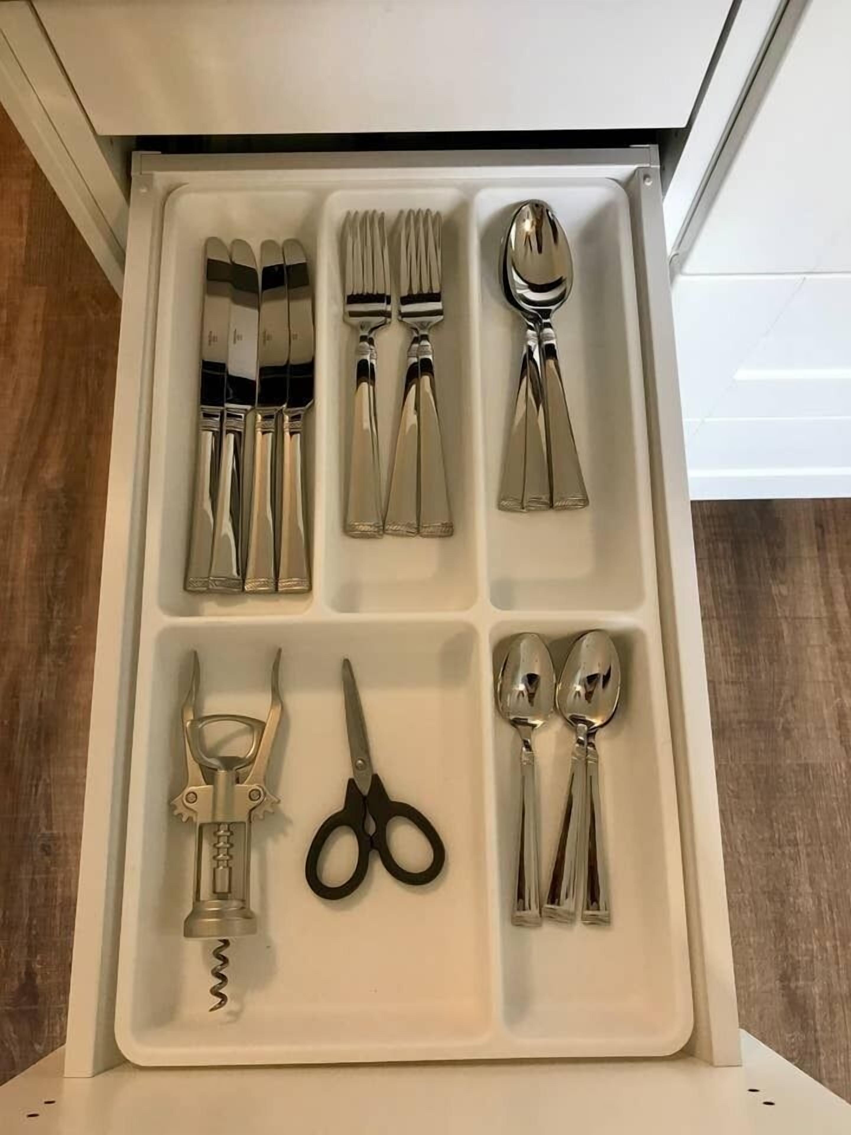 A drawer with neatly organized kitchen utensils including forks, spoons, and a pair of scissors.