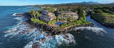 A coastal property with multiple buildings, a swimming pool, and a rocky shoreline.
