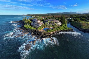 A coastal property with multiple buildings, a swimming pool, and a rocky shoreline.