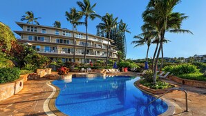 A hotel with a swimming pool, palm trees, and a multi-story building. - Whalers Cove Unit #113 - Spectacular and Secluded Oceanfront Condo with Pool! (Koloa)