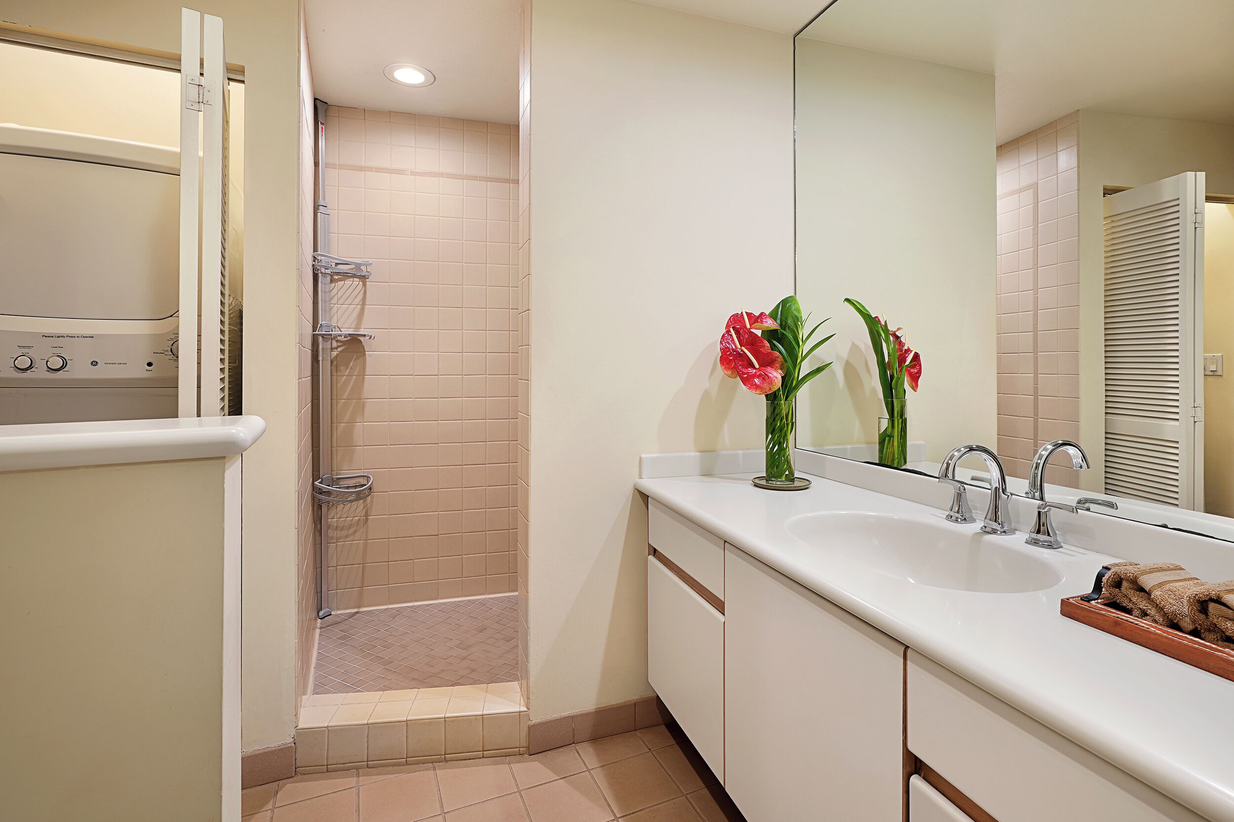 A modern bathroom with a walk-in shower, a large mirror, and a sink with a towel rack.