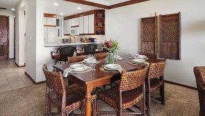 Un coin repas avec une table en bois dressée pour six personnes, entourée de chaises en osier.