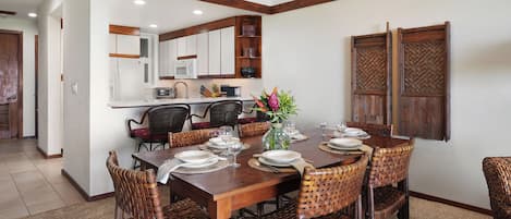 Comedor con mesa de madera dispuesta para seis personas, rodeado de sillas de mimbre.