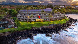 Un hôtel à plusieurs étages doté d’une piscine, situé près d’une côte rocheuse où les vagues déferlent.