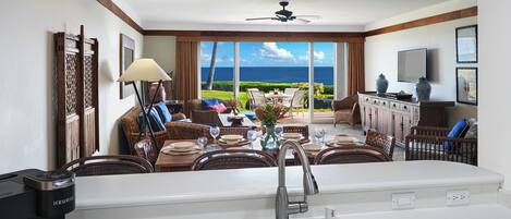 Quarto de hotel com cozinha compacta, área de refeições e vista para o oceano.