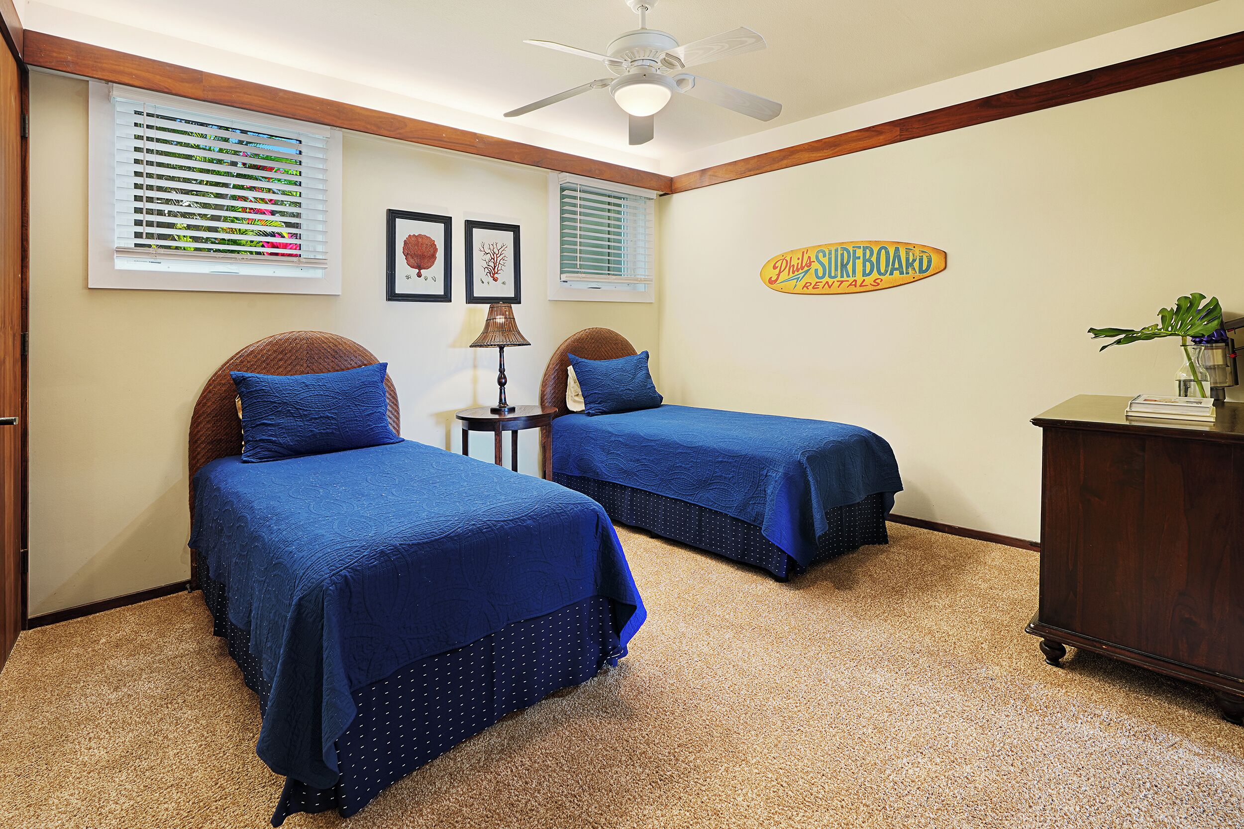 Une chambre avec deux lits, un ventilateur de plafond et un panneau décoratif mural.
