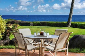 An outdoor seating area with a table and chairs, overlooking a body of water.