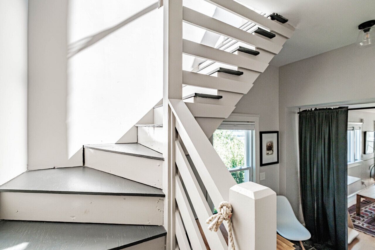 Una escalera moderna con barandillas blancas y vistas al exterior.