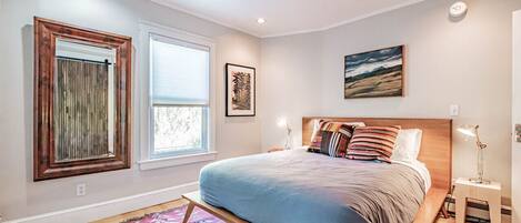 Une chambre à coucher avec un lit, une fenêtre, un tableau accroché au mur et une table de chevet.