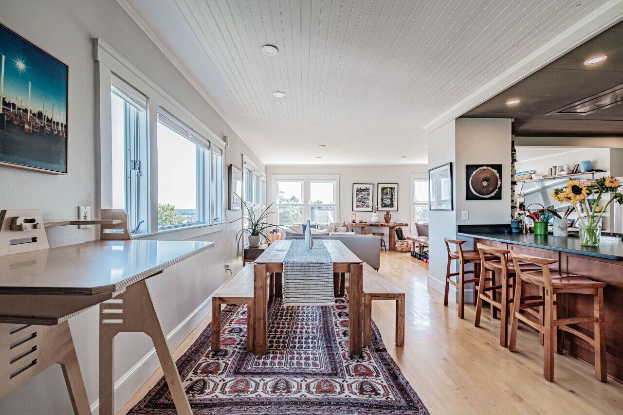 A spacious kitchen with a dining area, large windows, and a view of the outdoors.