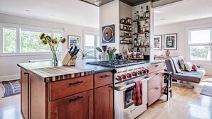 Una cocina moderna con una isla central, horno empotrado y una estantería para vinos.