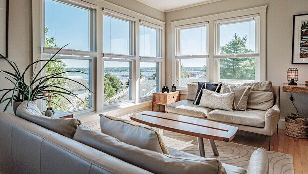Un amplio salón con ventanas grandes, un sofá, una mesa de centro y vistas a la ciudad.