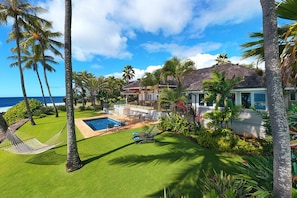 Un resort tropical con piscina, palmeras y vista al océano.