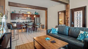Una sala de estar moderna con un sofá de cuero, una mesa de centro de madera y una cocina al fondo.