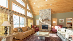 A spacious living room with a stone fireplace, leather sofas, and a large window providing natural light. - PRIVATE Luxury Lake Home with 5+ BR and Gourmet Kitchen-22 Foot Pontoon Included (Alexandria)