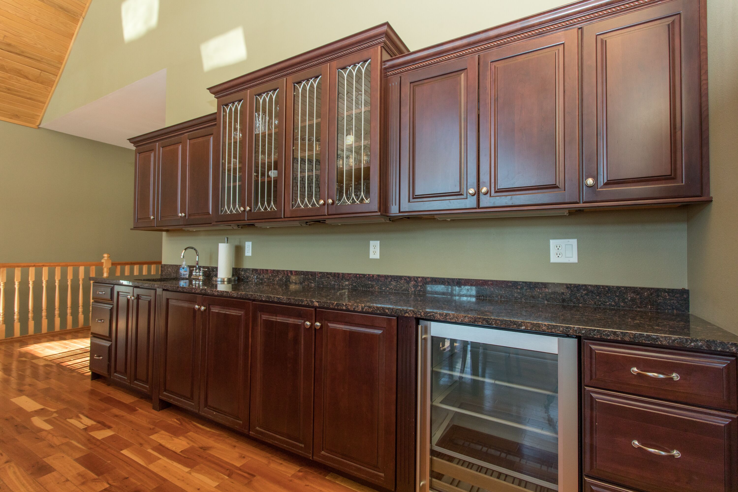 A kitchen with dark wooden cabinets, granite countertops, and a stainless steel dishwasher.