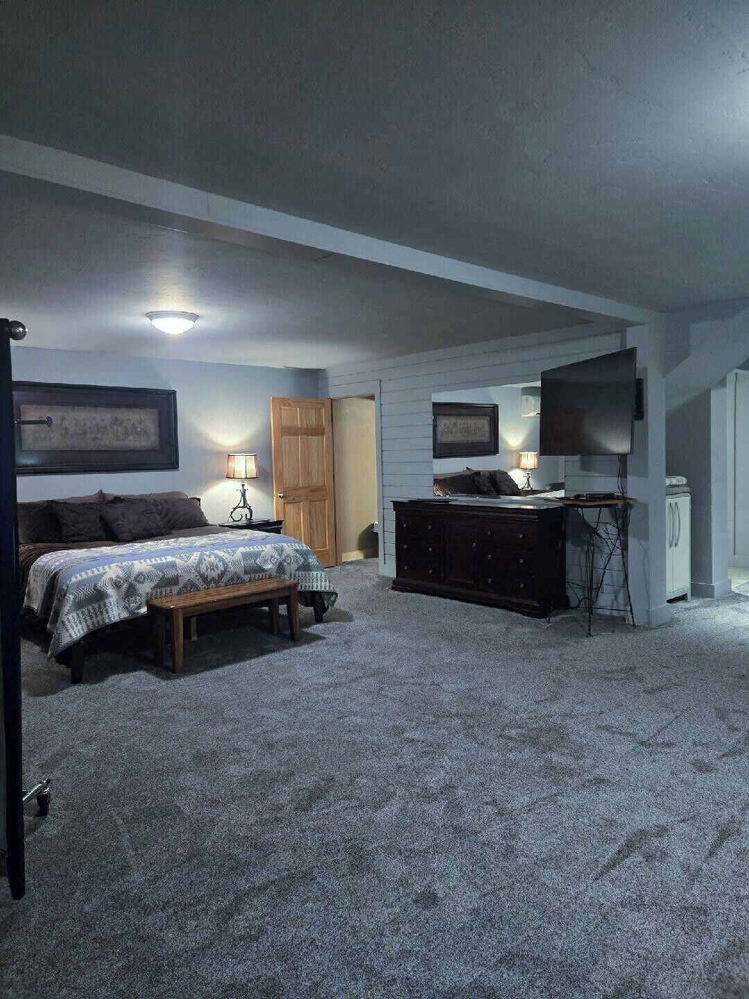 Een slaapkamer met een bed, een dressoir, een bureau en een televisie.