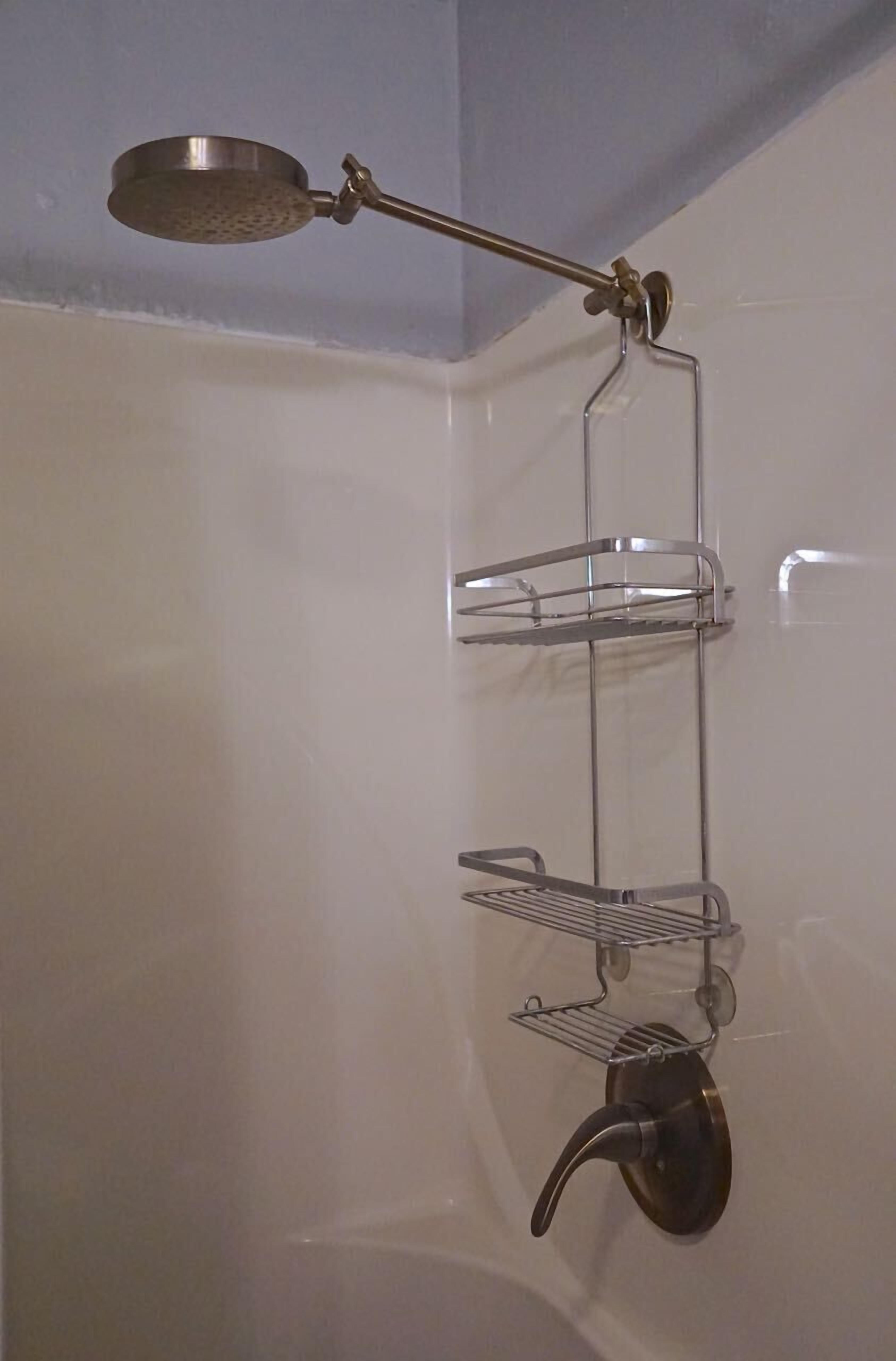 Een badkamer met een douche, een metalen rek en een hangende plantenbak.