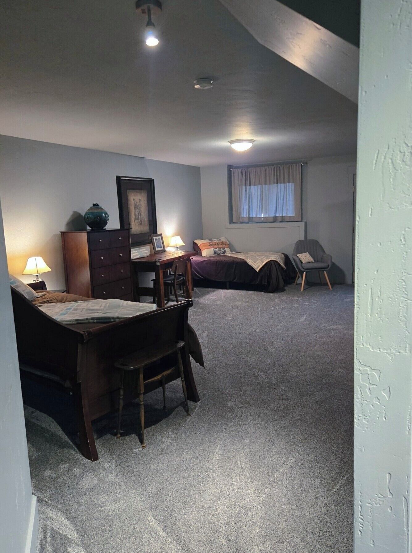A bedroom with a bed, a desk, a chair, and a window.