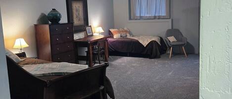 A bedroom with a bed, a desk, a chair, and a window.