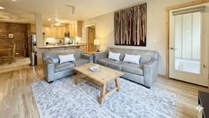 A modern living room with a sofa, coffee table, and a kitchen in the background.