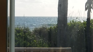Vista del océano a través de una ventana con barandilla de madera.