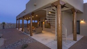 Une maison moderne dotée d’un patio couvert, d’un escalier en colimaçon et d’un mur de pierre en arrière-plan.