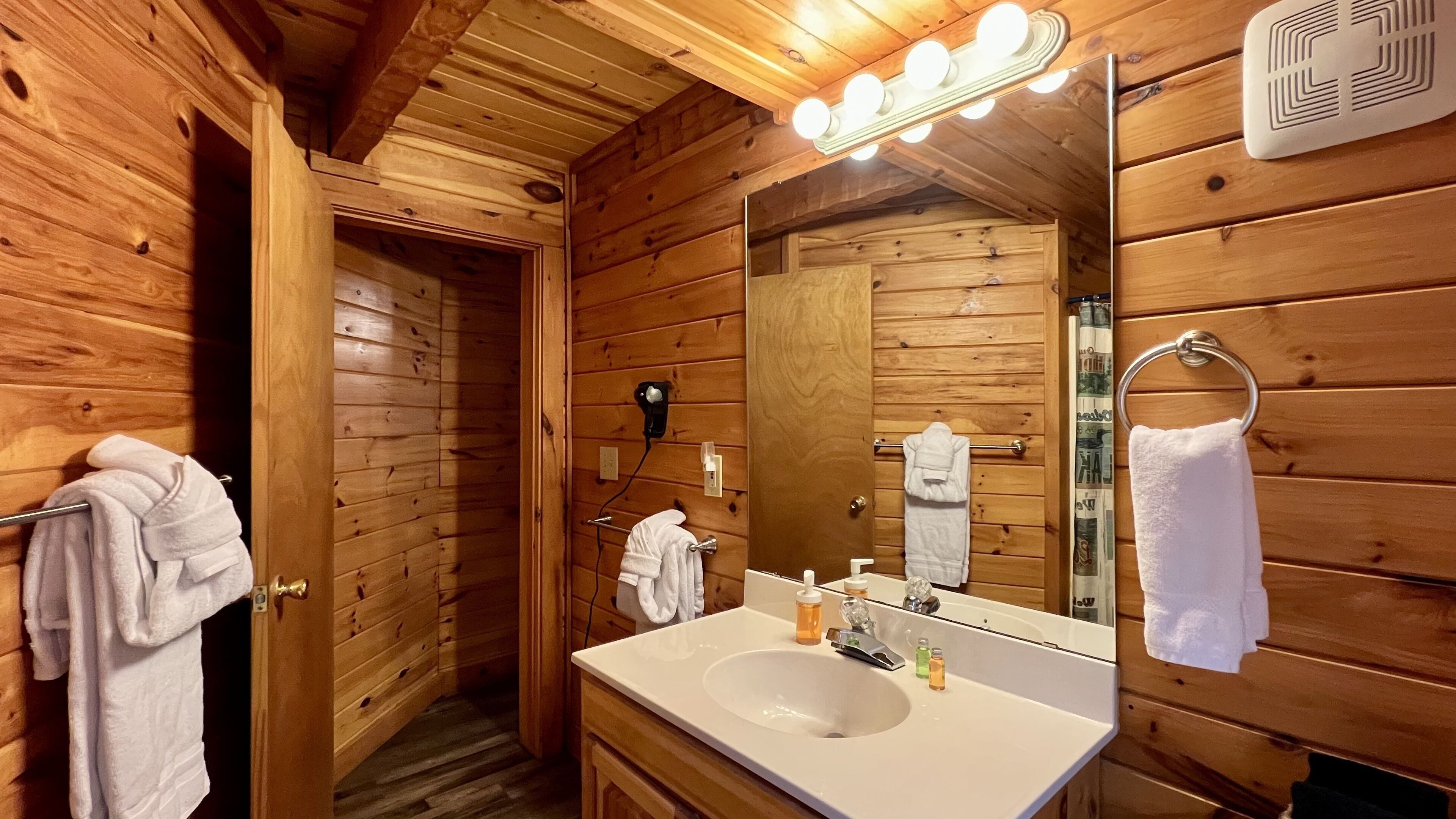 A wooden cabin bathroom with a sink, mirror, and towel rack.