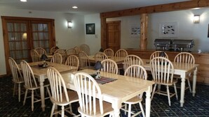 Un comedor con mesas y sillas de madera, una estación de buffet y una cocina al fondo.