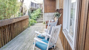 A wooden deck with a rocking chair and a table, a wooden fence, and a staircase leading to a building. - Spacious Santa Cruz Beach Home, Walk to the Ocean, Game Room, Pet Friendly! (Santa Cruz)