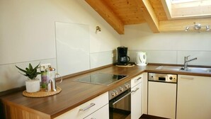 Una cocina con encimera de madera, cafetera, hervidor y lavavajillas.