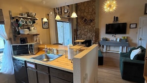 A modern kitchen with a central island, built-in appliances, and a stone accent wall.