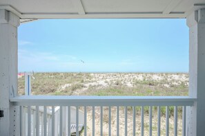 Un balcon blanc donnant sur une plage et des dunes.
