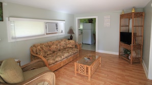 A living room with a sofa, a chair, a coffee table, and a wooden cabinet.
