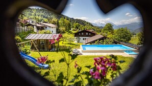 En hjärtformad sökare som visar en vy över ett bostadsområde med en swimmingpool, en rutschkana och hus med ett bergigt landskap i bakgrunden.