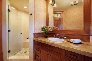 Une salle de bain avec une douche à parois de verre, un meuble-lavabo en bois et un miroir au-dessus.