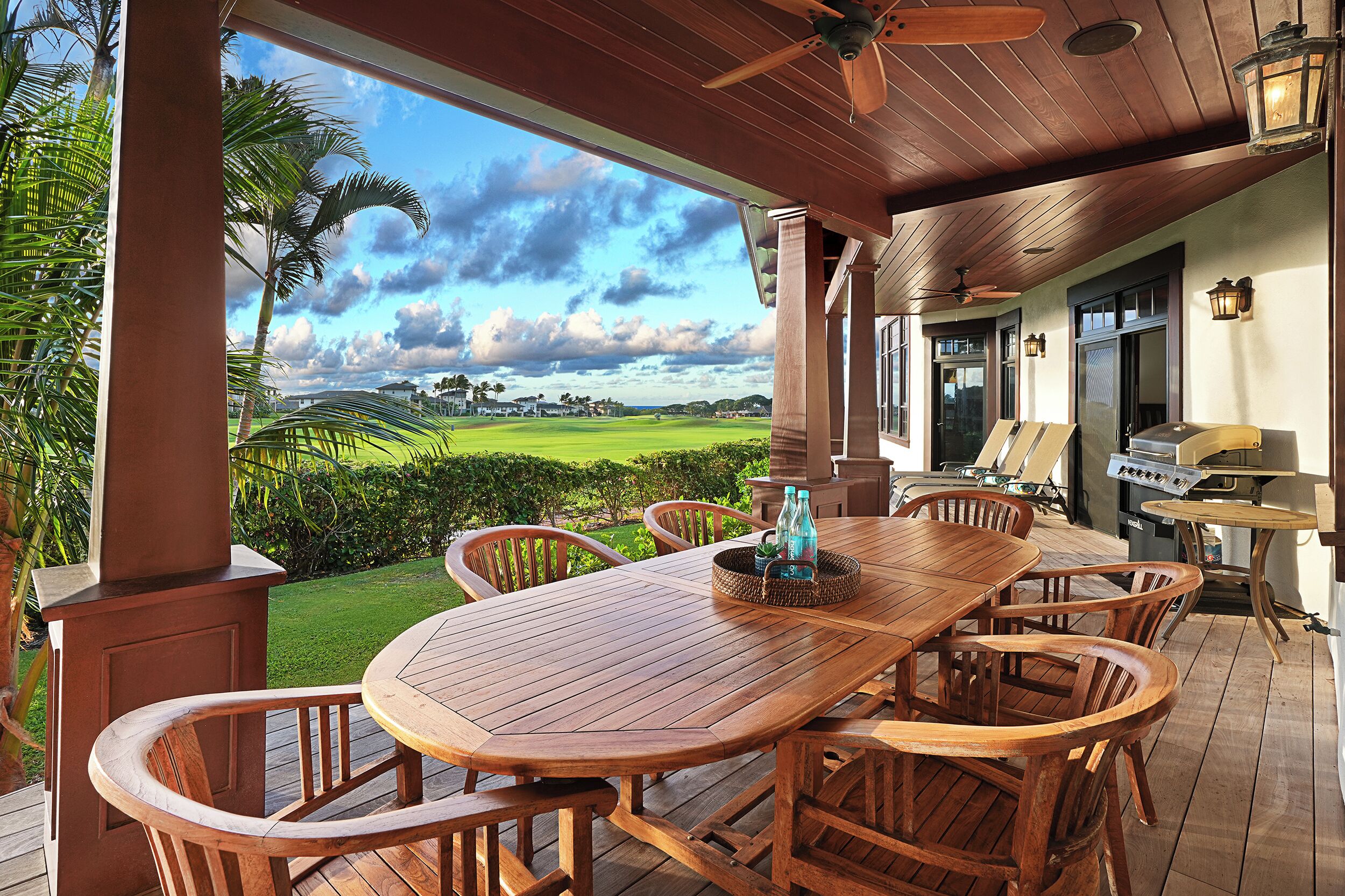A wooden deck with a table and chairs, overlooking a golf course.