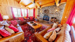 A cozy living room with wooden walls, a stone fireplace, and leather sofas with patterned cushions. - Perle du Bois - Ski in/Ski out (Kirkwood)