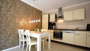 A modern kitchen with white cabinets, a dining table with chairs, and a patterned wallpaper. - House Morgenstern fantastic apartment (Göhren)