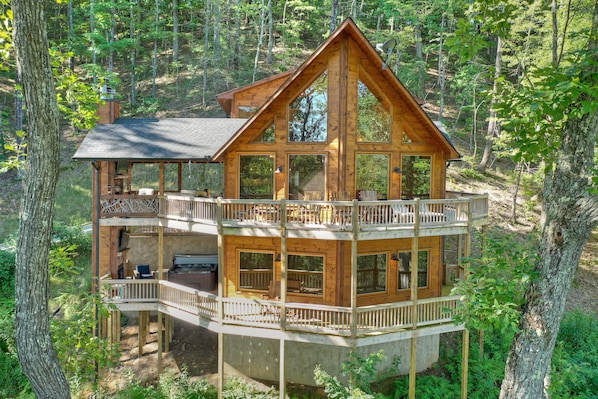 A multi-level wooden cabin with balconies, surrounded by forest.