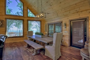 A wooden cabin interior with a dining table, benches, and a chair.