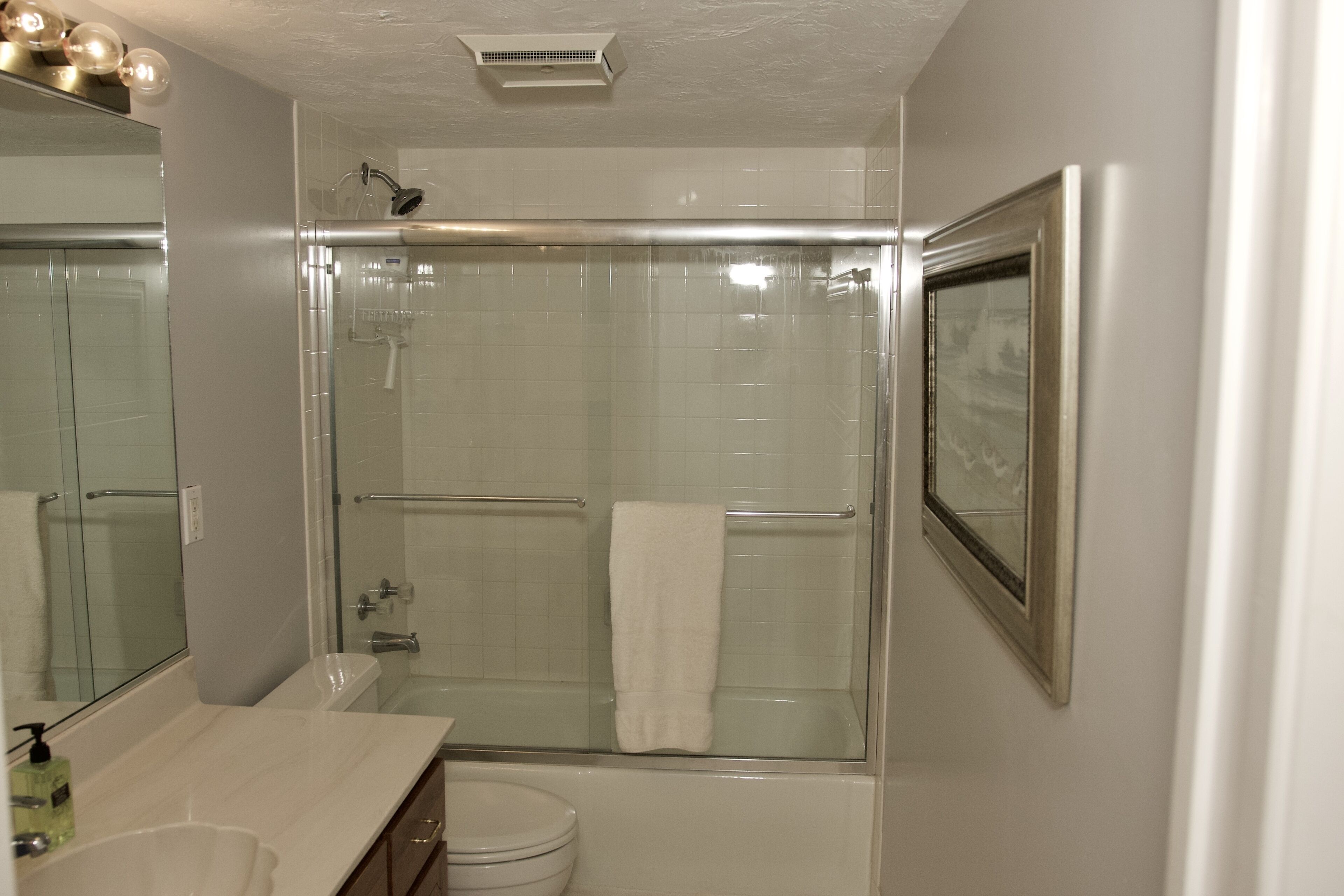 Ein modernes Badezimmer mit einer Duschkabine aus Glas, einem weißen Waschbecken und einer Toilette.