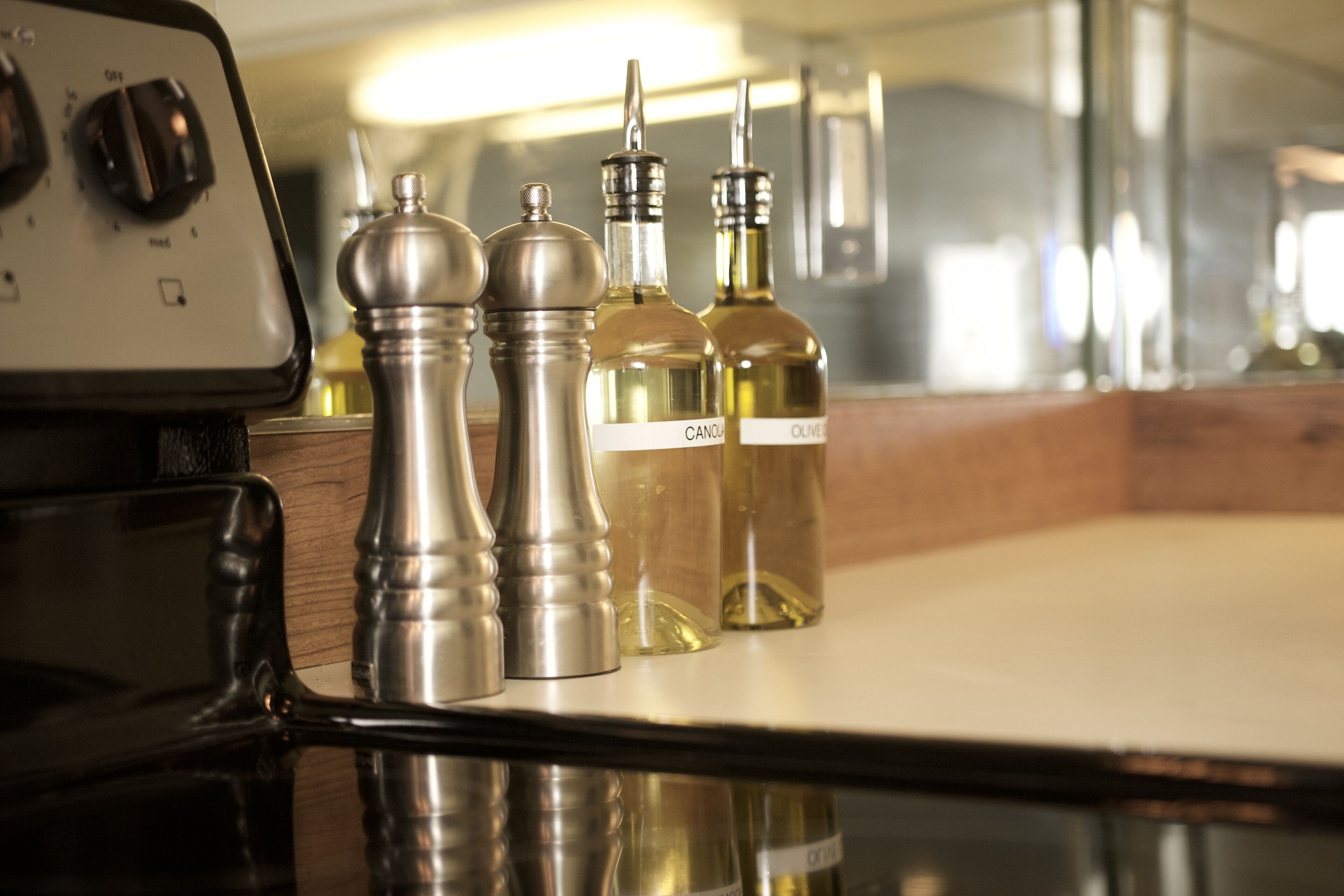 Una encimera de cocina con saleros y pimenteros, una estufa y botellas de aceite de oliva.