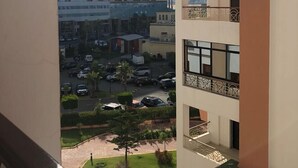 Un immeuble à plusieurs étages doté de balcons, offrant une vue sur un parking et un restaurant McDonald's.